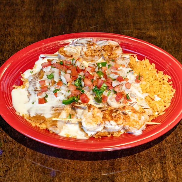 Grilled shrimp skewers with pico de gallo, white sauce, and Mexican rice on a red plate.