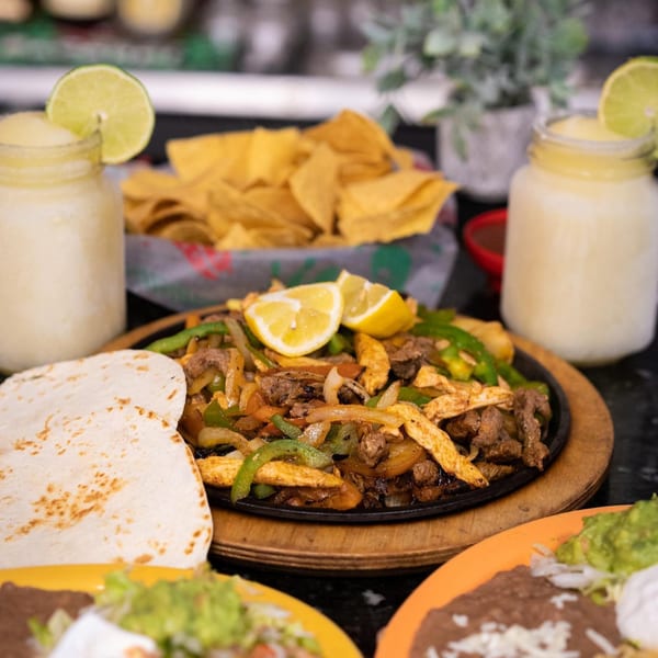 Sizzling fajitas with tortillas, chips, and two frozen margaritas at Los Mariachis Mexican Restaurant.