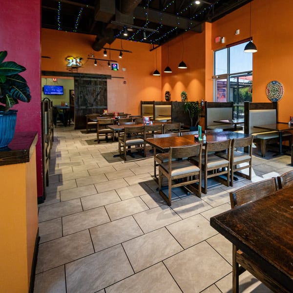 Spacious dining area at Los Mariachis Mexican Restaurant with orange walls, wooden tables, and booths.
