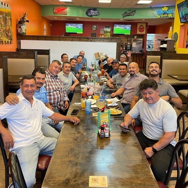 Group of men smiling and posing for a photo at a long table in Los Mariachis Mexican Restaurant.